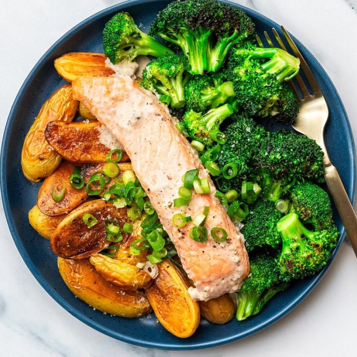 Roasted salmon with potatoes and broccoli on a navy plate