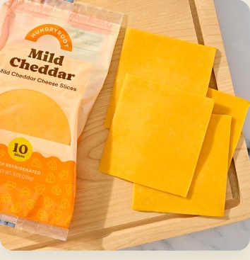 Mild cheddar cheese slices on a wooden board