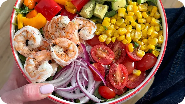 Colorful food bowl with shrimp, corn, bell peppers, tomatoes, and red onions