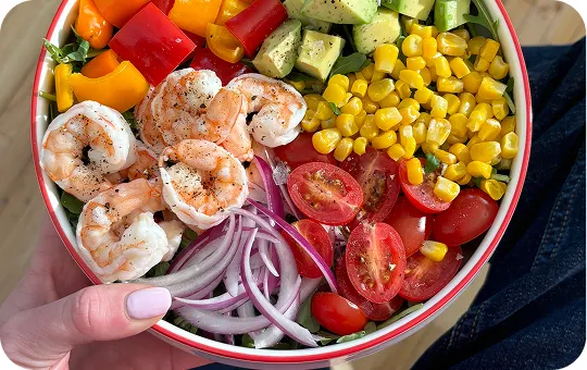 Colorful food bowl with shrimp, corn, bell peppers, tomatoes, and red onions